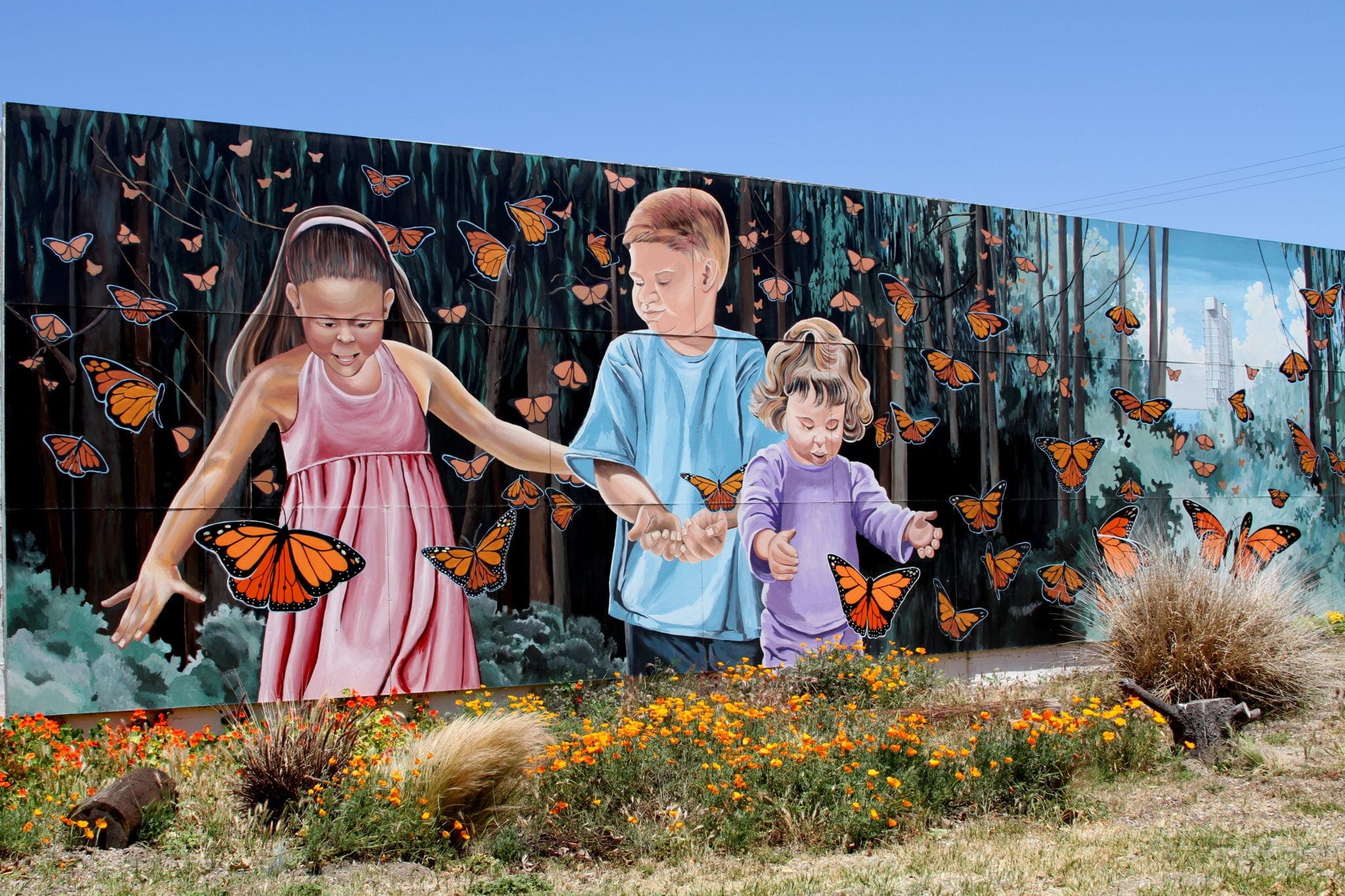 A colorful mural depicts a trio of kids surrounded by orange and black monarch butterflies