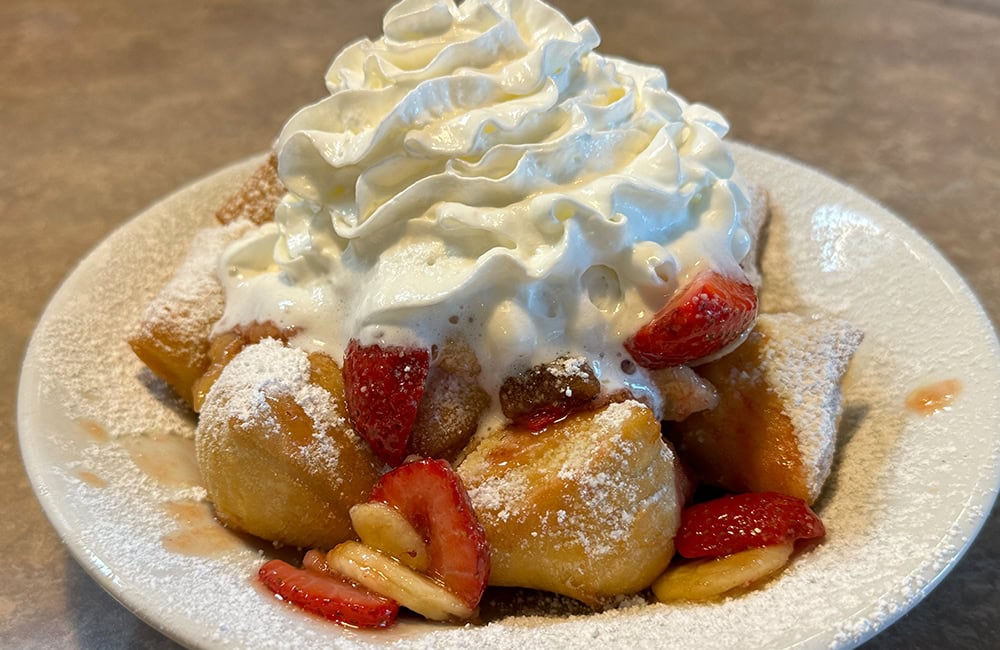 Creamy whipped topping with strawberries and fried dough on a dessert plate, Lompoc California.
