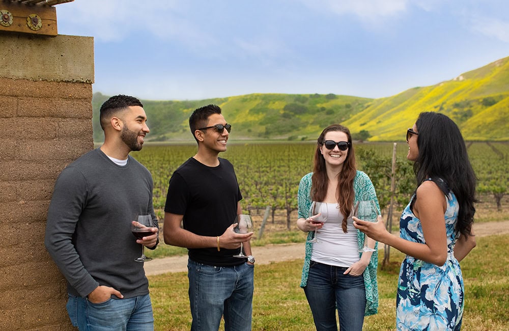 Group of friends enjoying wine tasting at a vineyard in Lompoc, California.