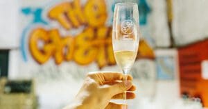 Closeup of a champagne glass with the Flying Goat logo and the words 'goat bubbles'