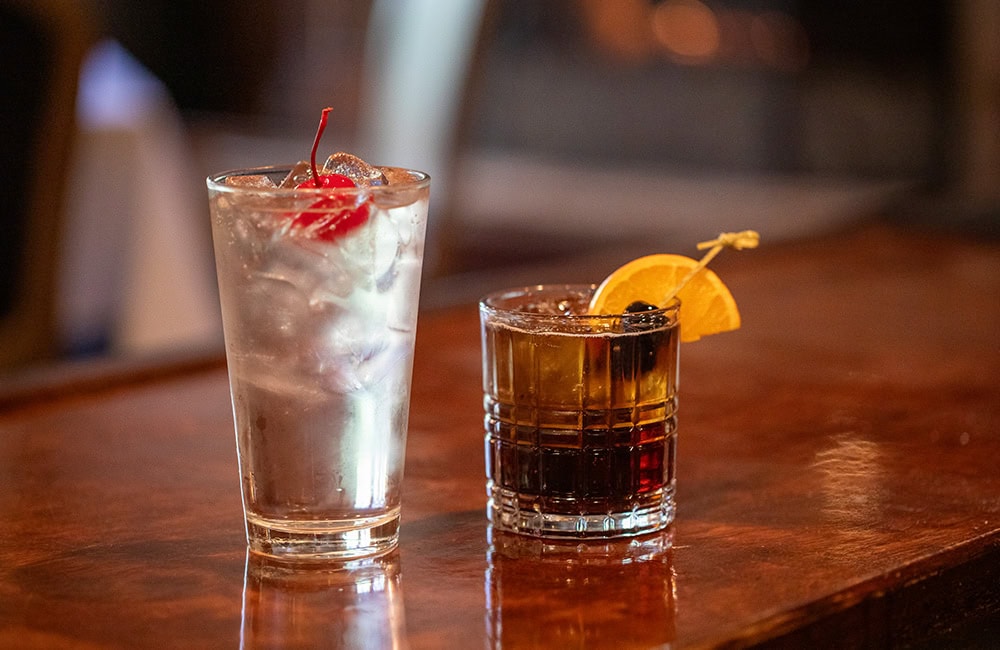 Two cocktails on a wooden bar counter in Lompoc California, Jasper's restaurant.