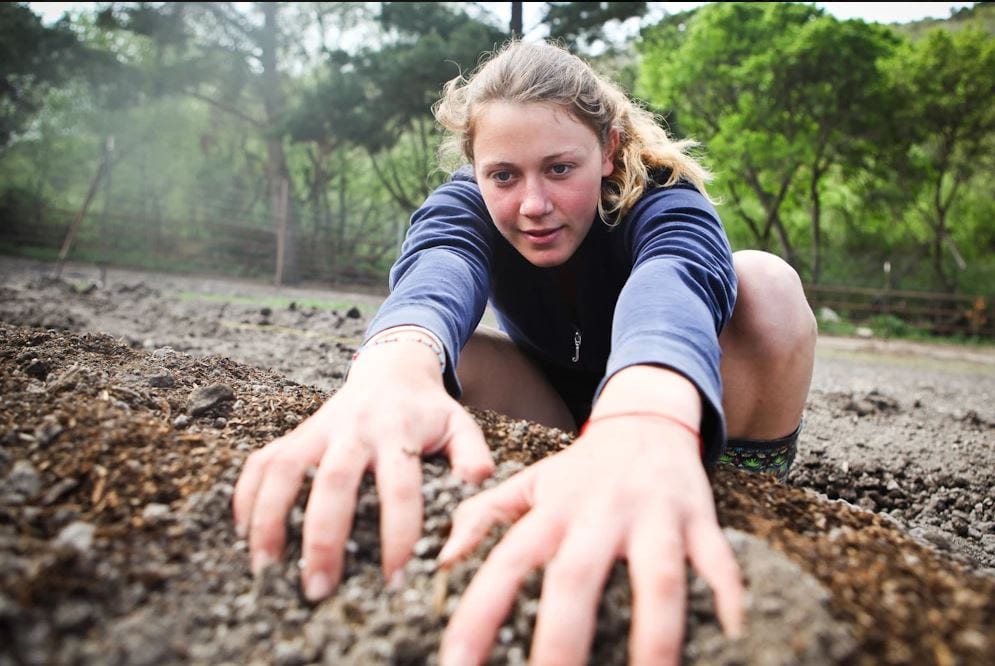 Girl running hands through dirt