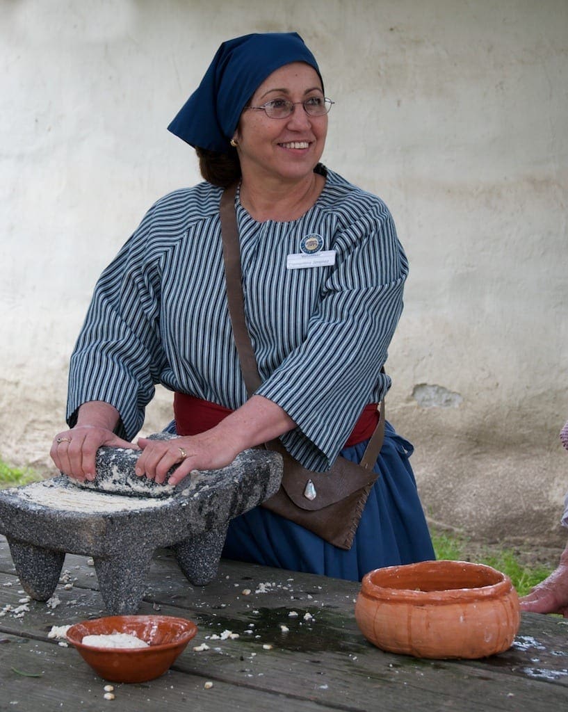 A volunteer at La Purisima Mission demonstrates grinding nixtamal into masa
