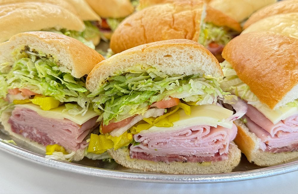 Fresh deli sandwiches with lettuce, ham, and cheese on a platter in Lompoc, California.