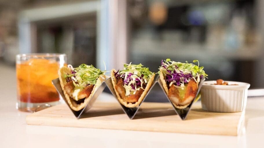 A trio of fish tacos with fresh toppings and a fancy drink at Valle Eatery + Bar