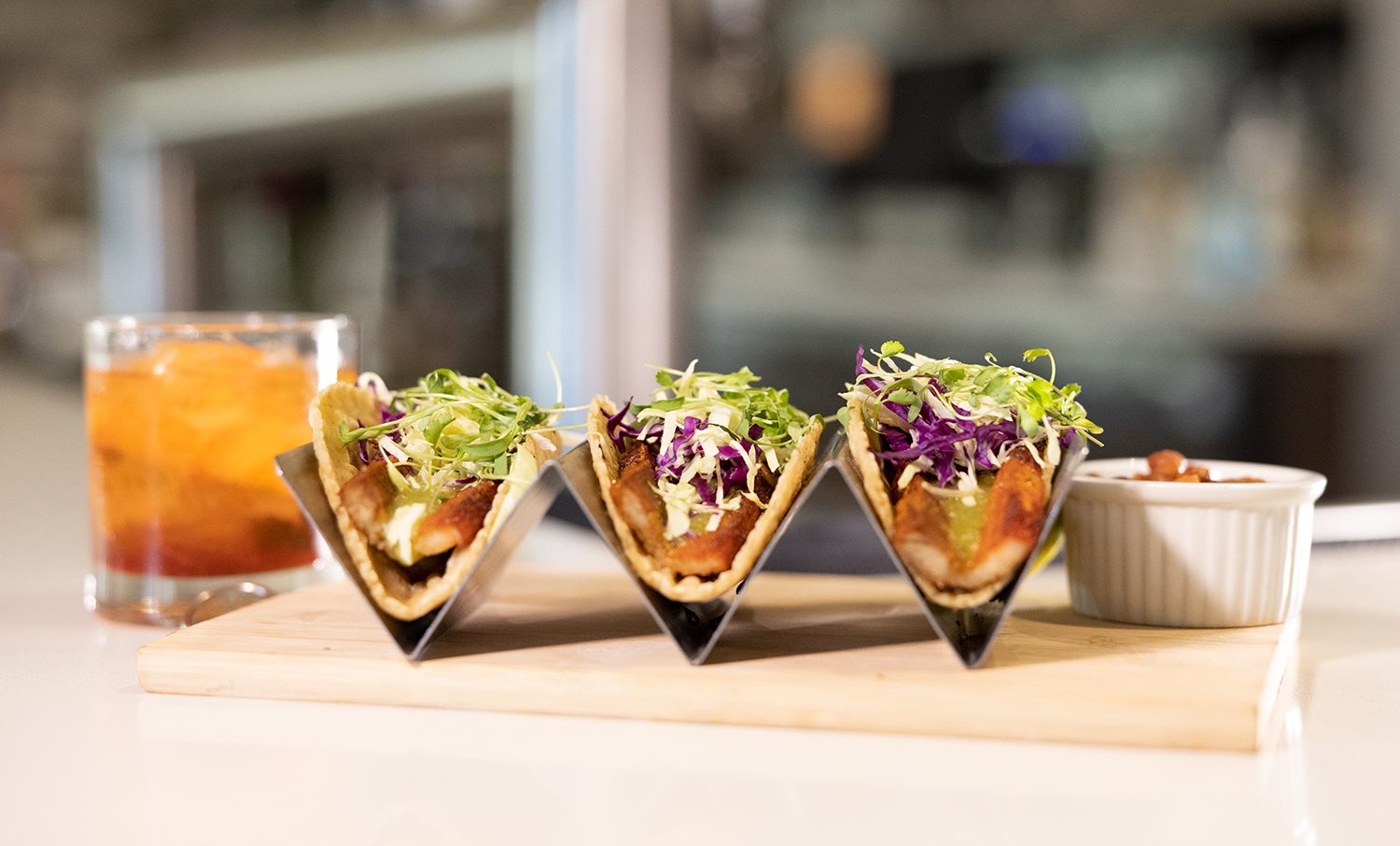A trio of fish tacos with fresh toppings and a fancy drink at Valle Eatery + Bar