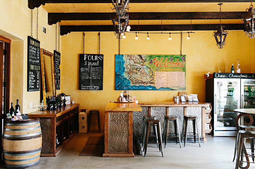 Interior view of Montemar Winery; with a rustic bar, metal stools and hand painted signage