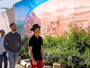 A trio walks past a mural depicting settlers in downtown Lompoc