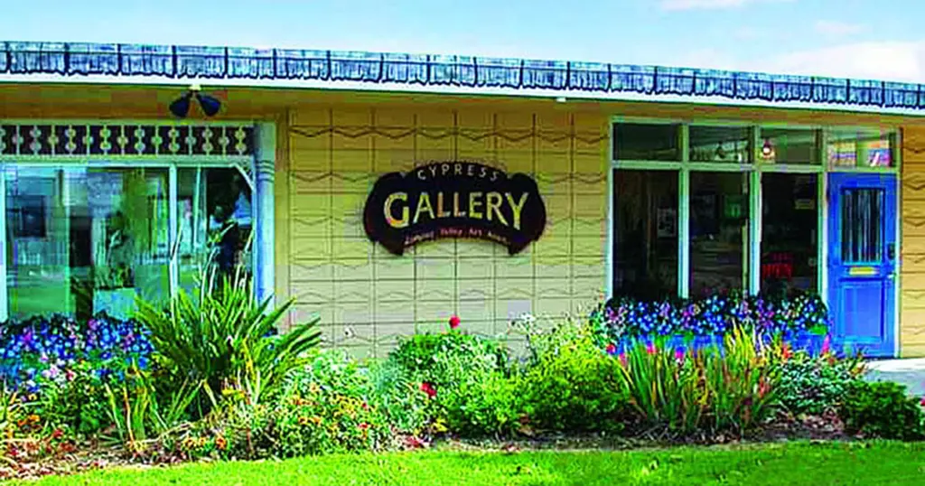 Exterior photo of the brightly blue-and-yellow painted Cypress Gallery