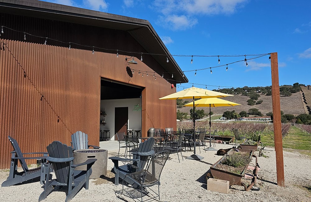 Outdoor patio at a Lompoc winery with tables, chairs, and yellow umbrella.