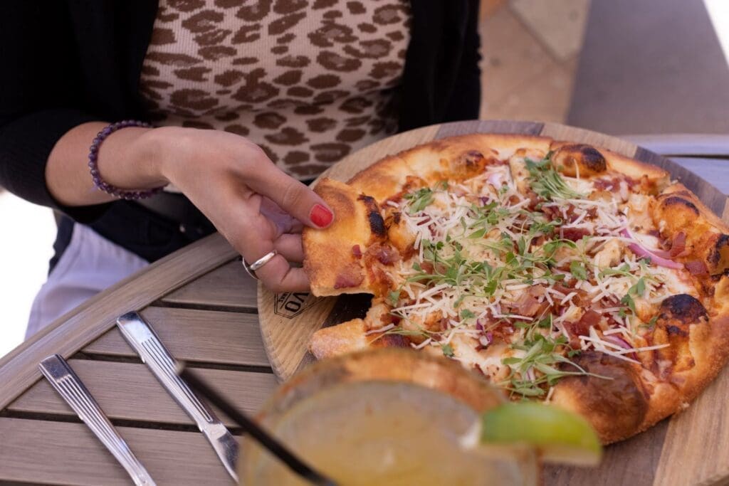 Photo of a hand grabbin a slice of pizza on a table