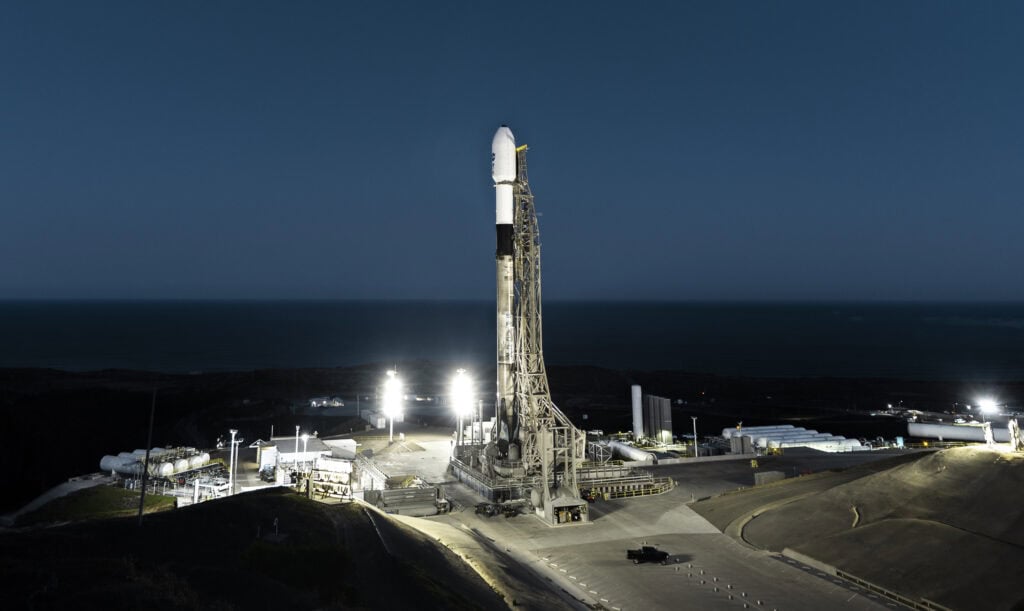 Lompoc California rocket launch pad at night with illuminated infrastructure and ocean view.