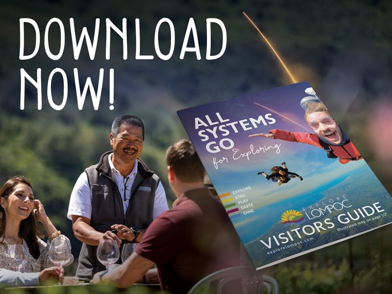 Explore Lompoc California visitors guide brochure being handed out outdoors.