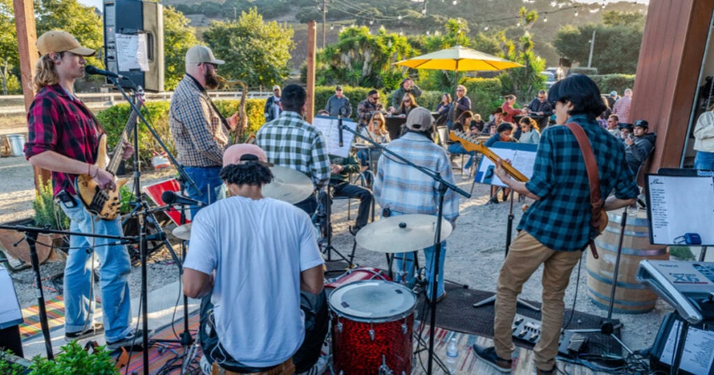 Musicians playing guitars and drums outdoors during a local event in Lompoc.