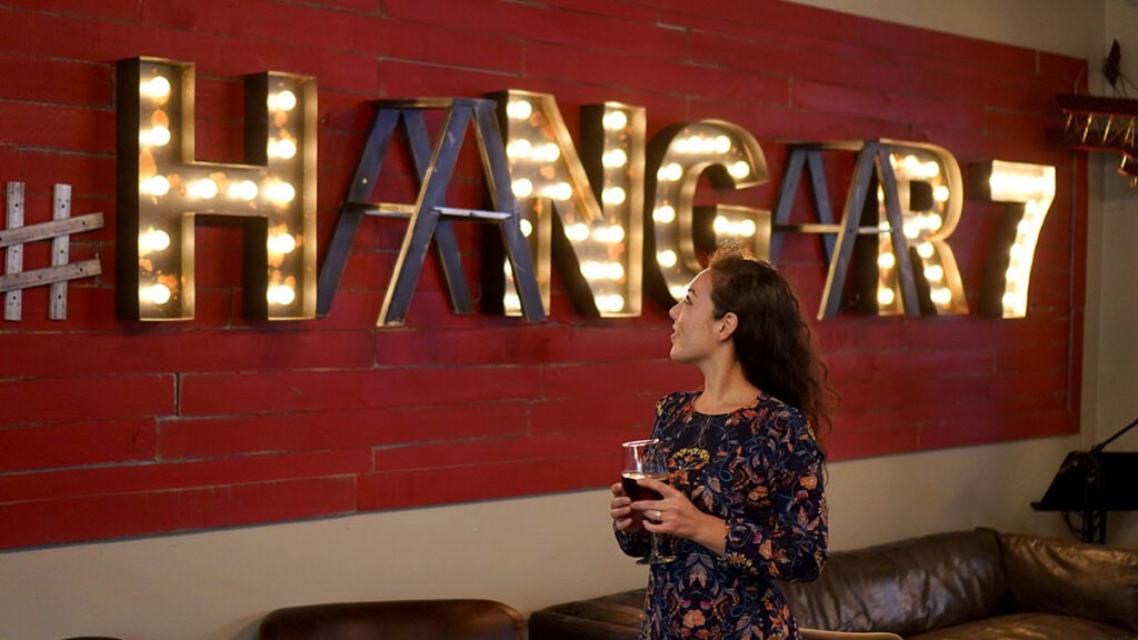 Woman holding wine glass near Hangar7 sign in Lompoc, California.