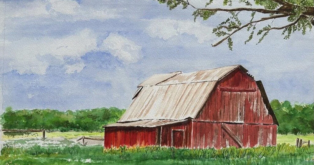 Old red barn in Lompoc, California with lush greenery and blue sky.
