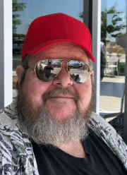 Man with a beard, sunglasses, and red cap outdoors in Lompoc, California.