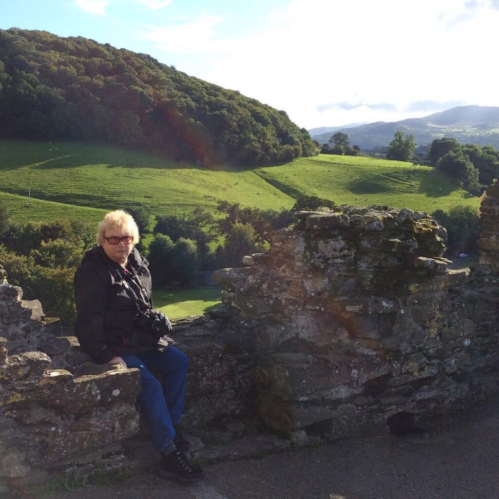 Woman sitting on stone ruins with lush green hills in Lompoc California background.