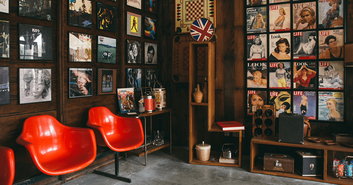 Interior of a vintage record store with red chairs and music magazine covers.