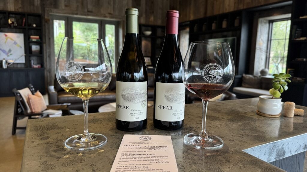 Two bottles of wine with glasses of white and red wine on a tasting table in Lompoc.