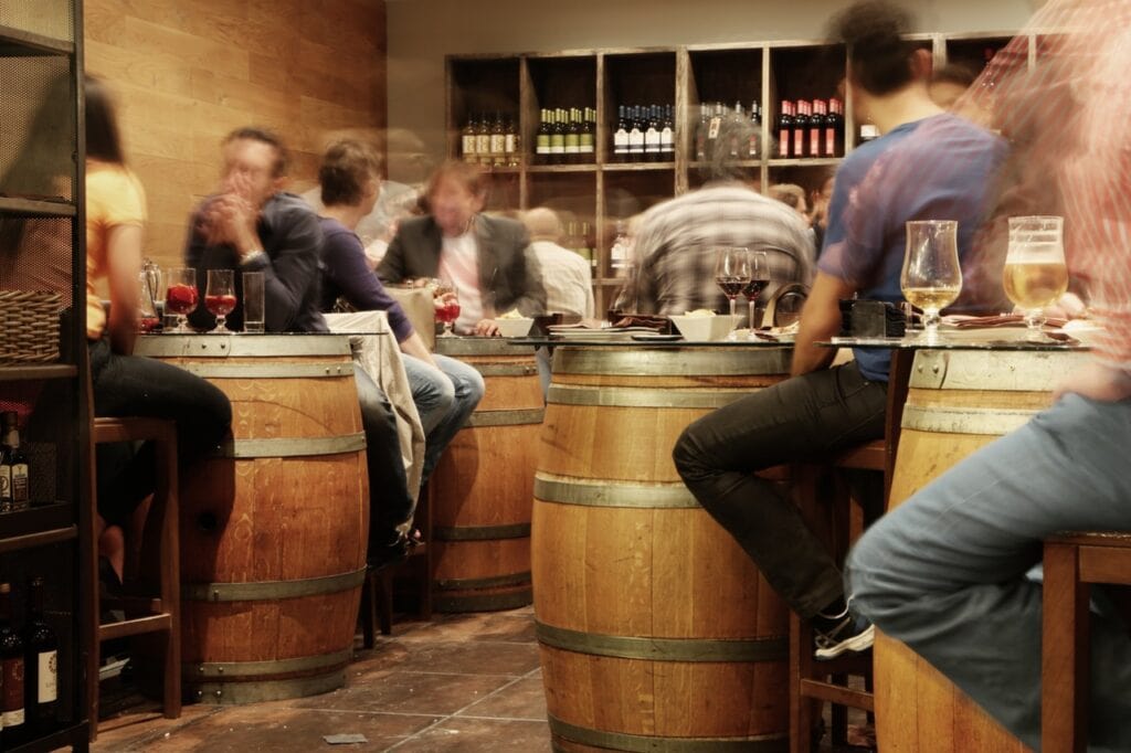People enjoying wine tasting at a cozy Lompoc winery with barrels and wine bottles.
